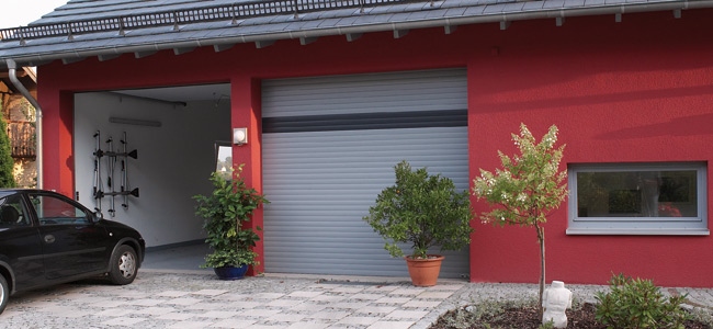 Graues Rolltor für die Garage vor roter Wand von Roma